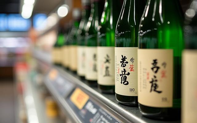 伝統的な日本酒のボトルとモダンな英文ラベルが海外のスーパーで並んでいる様子